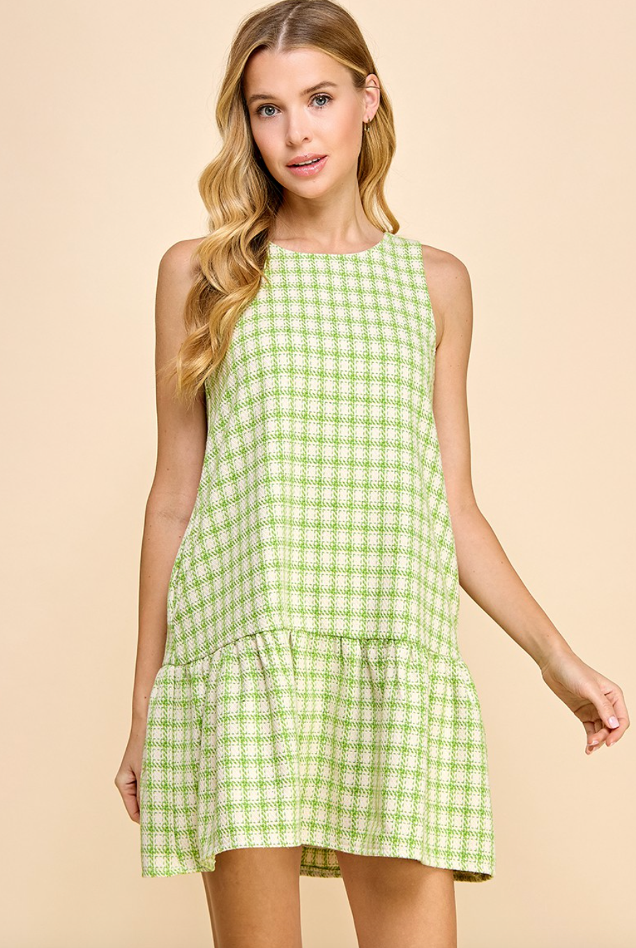 Model in green and white plaid dress with ruffle at bottom